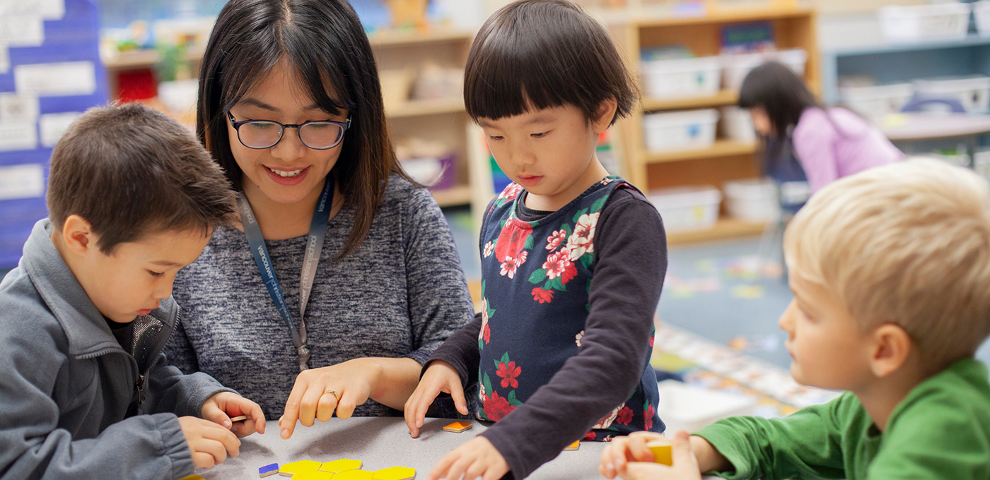 Elementary students gathered around teacher working on math